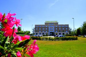 皮亚韦河畔诺文塔奥姆尼亚酒店的一座建筑,上面有标志,上面有粉红色的花朵