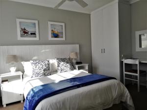 布鲁堡史特兰Dolphin Inn Blouberg的一间卧室配有一张带蓝白色床单的大床