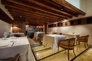 马略卡岛帕尔马Es Princep - The Leading Hotels of the World的餐厅设有白色的桌椅和木制天花板。