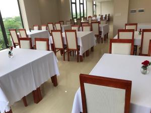 洞海Windy Hotel Quang Binh的一间设有白色桌椅的用餐室