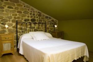 Arenas de IguñaPosada El Arrabal的一间卧室设有一张床和石墙