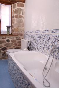 Arenas de IguñaPosada El Arrabal的带浴缸的浴室和石墙