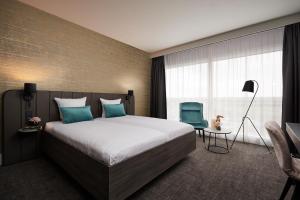 迭戈姆布鲁塞尔机场范德瓦尔克酒店的一间卧室配有一张大床和一张蓝色椅子