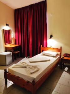 卡尔帕索斯Titania Hotel Karpathos的一间卧室配有一张带红色窗帘的床