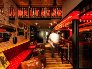 布达佩斯BALTAZÁR Boutique Hotel的一个人走进一个有红色长凳的酒吧
