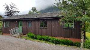 巴拉胡利什Oak Tree Lodge的一间设有绿门和砂石车道的小小屋