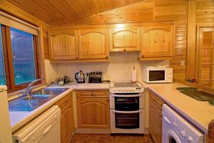 格伦科Rowan Tree Lodge的厨房配有木制橱柜和白色炉灶烤箱。