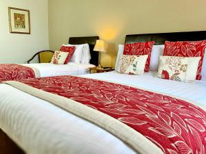 基拉尼翠鸟旅馆的配有红白毯子的酒店客房内的两张床