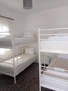 伊奥斯乔拉Grandma Vasiliki Rooms To Let的一间设有两张双层床和白色架子的房间