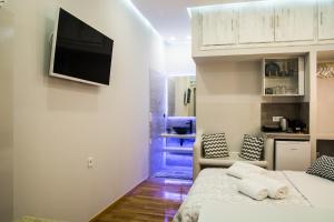 纳夫普利翁Nature's Guesthouse Luxury Nafplio的一间卧室配有一张床,墙上配有电视