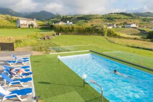 Algarvia阿尔加威亚坎普乡村民宿的游泳池设有椅子,人们在游泳池里游泳