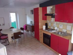 拉让提耶尔triplex douillet的厨房配有红色橱柜、桌子和水槽
