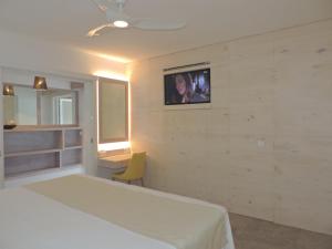 古斯塔维亚昂迪尼斯海滩酒店的卧室配有一张床,墙上配有电视。