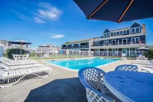 法尔茅斯Beachside Village Resort, a VRI resort的一座带桌椅的游泳池以及一座建筑