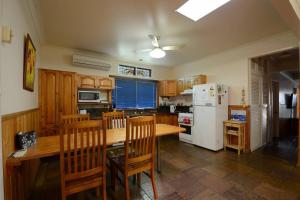 蚬壳港Seahaven Beach House - Shellharbour的厨房配有木桌和白色冰箱。