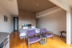 伊东UMITO the salon IZU的一间卧室配有一张床和紫色椅子