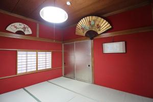 高冈市Maidohaya Fukutatei的一间空房间,有红色的墙壁和两个窗户
