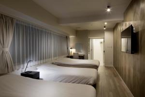 东京东京新宿区N.U.T.S酒店的酒店客房设有三张床和窗户。