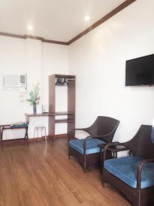 科隆Blue Waters Inn Coron Palawan的客厅配有椅子和平面电视