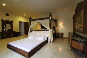 日惹griya desa hotel & pool的一间卧室配有一张带天蓬的大床