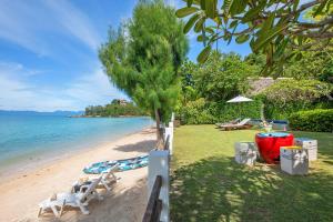 湄南海滩The Emerald Hill Beach Villa的海滩上,有两把白色椅子和一棵树