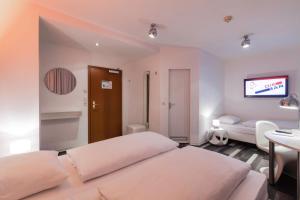 汉堡莫纳帕尔城市酒店的一间卧室设有两张床,墙上配有电视。