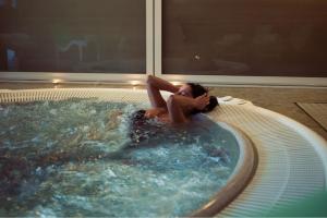 塞斯特雷Grand Hotel Sestriere的躺在室内热水浴池中的女人
