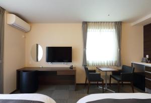 广岛HOTEL PROMOTE HIROSHIMA的酒店客房配有书桌和电视。