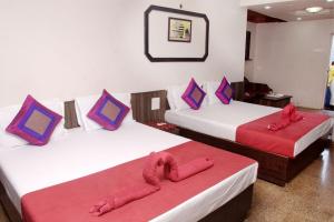 帕纳吉Viva Guest House的两张位于酒店客房的床铺,配有红色床单