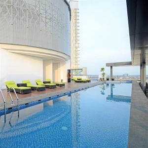 泗水Midtown Residence Surabaya的一座游泳池,旁边是一座黄椅
