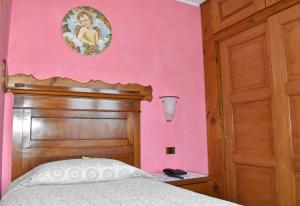科利科康卡阿祖拉阿尔伯格餐厅酒店的一间卧室设有粉红色的墙壁和一张带木制床头板的床