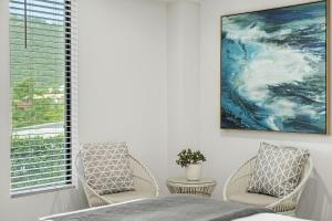 埃尔利海滩Airlie Guest House的卧室配有两把椅子,墙上挂有绘画作品