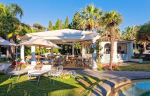 伊斯基亚La Reginella Resort & Spa的游泳池旁带桌子和遮阳伞的天井
