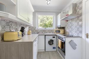邓弗姆林No 46 - by StayDunfermline的白色的厨房配有洗衣机和窗户。