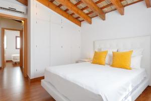 赫雷斯-德拉弗龙特拉雪利中心公寓的白色卧室配有白色床和黄色枕头