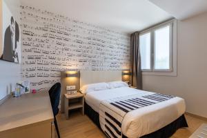 圣塞瓦斯蒂安Casual del Jazz San Sebastián的一间卧室设有一张床和一张写字墙