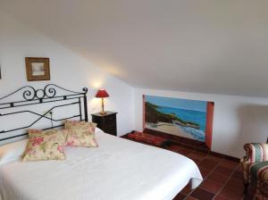 里瓦德塞利亚Hotel Rural El Pagadín的卧室配有白色的床和墙上的绘画作品