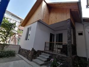 博尔若米Ira & Vaso's guest house Borjomipark的白色的小房子,设有木屋顶