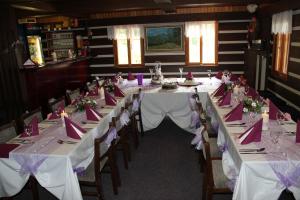 贝内茨科Pension Alex的一间长餐厅,配有白色的桌子和椅子