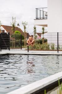 米德尔克尔克C-Hotels Zeegalm的坐在游泳池旁的杆子上的人