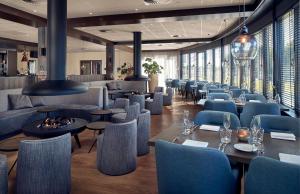 内斯Fletcher Hotel-Restaurant Noordsee-Ameland的餐厅设有蓝色的椅子和桌子以及窗户。