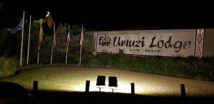 塞昆达Umuzi Lodge的两把椅子坐在沙子里的标志前