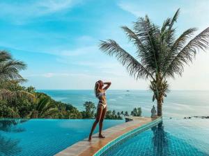 Haad Chao PhaoSunset Hill Boutique Resort Koh Phangan的站在一个棕榈树游泳池旁的女人