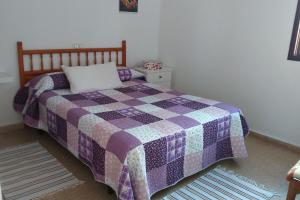 蓬塔德尔西达尔戈Surfing the Blue II的卧室在床上配有紫色和紫色的被子