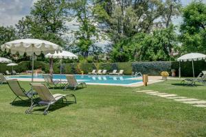 维罗纳Cà dell'Orto Rooms & Apartments的草地上带椅子和遮阳伞的游泳池