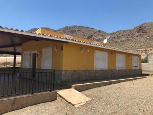 阿桂拉斯Casa Rural Aguilas (Murcia), Venta San Felipe的黄色的建筑,有白色的门和栅栏