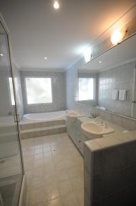 曼哲拉曼杜拉码头度假村的浴室配有2个盥洗盆、浴缸和淋浴。