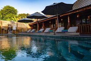 蓝梦岛Royal Cottage Nusa Lembongan的一个带躺椅和遮阳伞的游泳池
