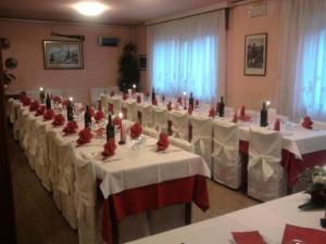 福扎Hotel Monte Fior的宴会厅配有白色桌子、红色椅子和蜡烛