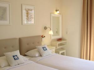斯派赛斯Alexandris Hotel的一间白色卧室,配有两张床和镜子